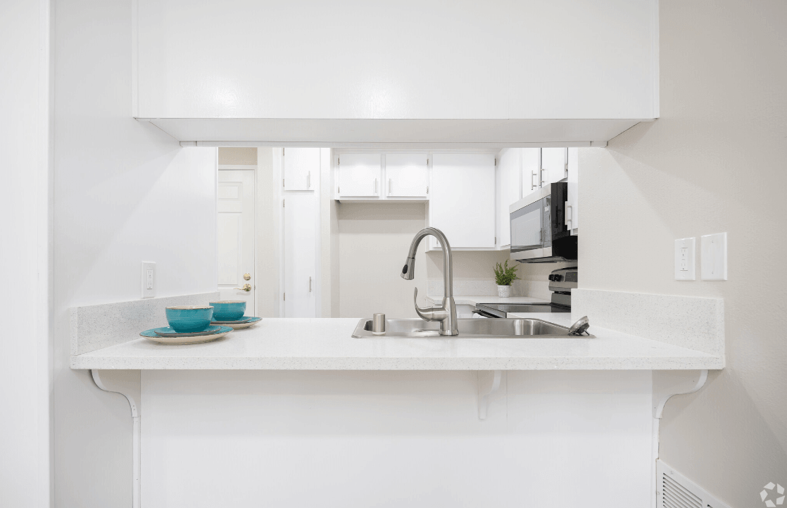 a white kitchen with a sink and a counter top at Huntington Terrace North Senior, California